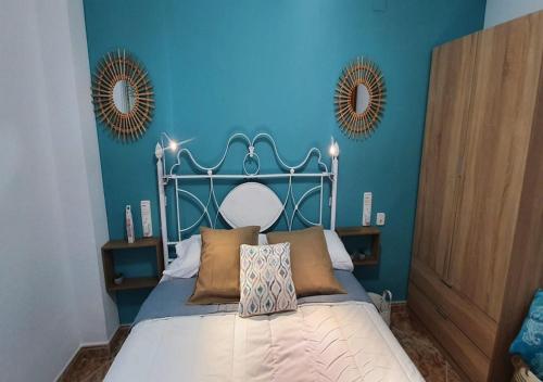 a bedroom with a bed with blue walls and mirrors at Monela Front beach in Playa de Gandia