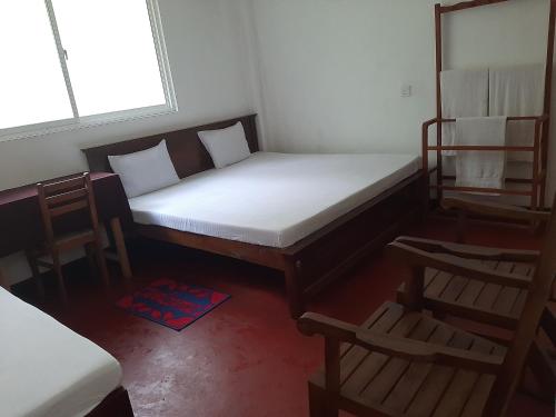 Hotel Yelona في كيجالي: غرفة نوم صغيرة بسرير وكرسيين