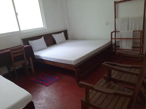 een kleine slaapkamer met een bed en 2 stoelen bij Hotel Yelona in Kegalle