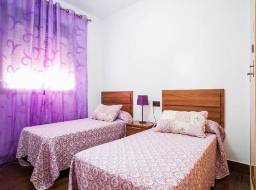 two beds in a room with purple curtains at CASA VARAVILLA in Conil de la Frontera