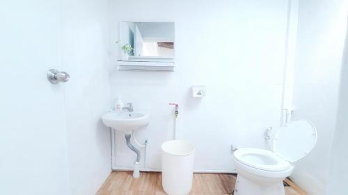 La salle de bains blanche est pourvue de toilettes et d'un lavabo. dans l'établissement Najai Home Stay lamphun, à Lamphun