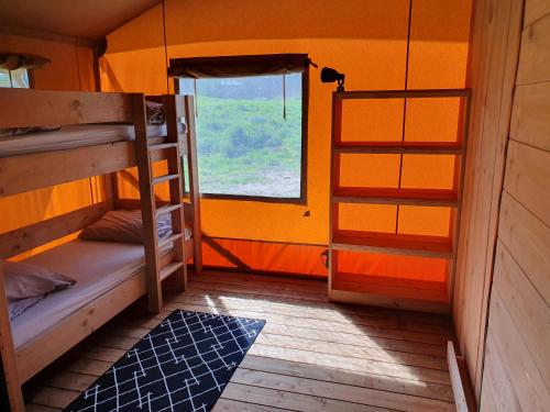 une chambre avec deux lits superposés et une fenêtre dans l'établissement Luxury Safari Tents at Moulin Du Pommier Glamping & Camping, à Saulgond