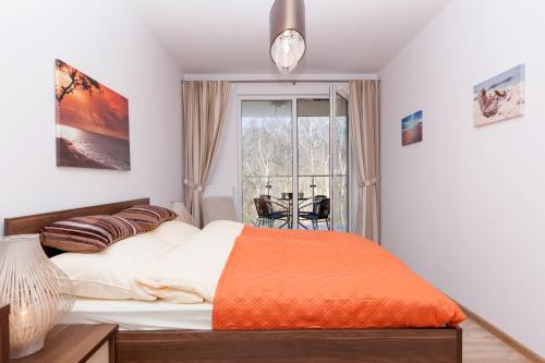 ein Schlafzimmer mit einem großen Bett mit einer orangefarbenen Decke in der Unterkunft Apartament Deluxe Polanki z Garazem in Kołobrzeg