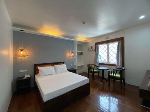 a bedroom with a bed and a table and a window at Dumaguete Seafront Hotel in Dumaguete