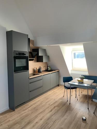 City-Apartment Düsseldorf في دوسلدورف: مطبخ مع أجهزة ستانلس ستيل وطاولة