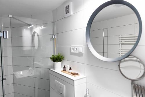 Baño blanco con espejo y lavabo en Roomstore Studio Apartments en Eger