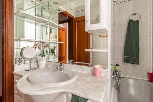 ein Badezimmer mit einem Waschbecken, einem Spiegel und einer Badewanne in der Unterkunft Casa Julia playa de Berria in Santoña