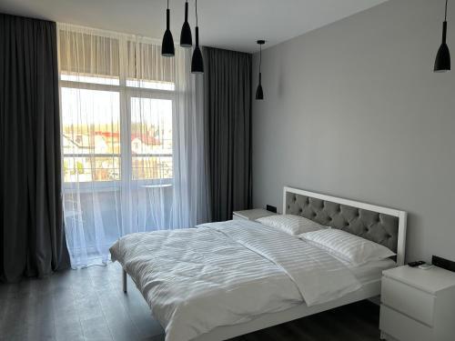 a white bedroom with a large bed and a window at EAvalonRestApartment in Lviv