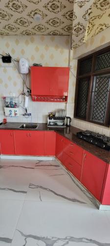 a kitchen with red cabinets and a sink at Casa Arhan 2-3-4-7-12 BHK Luxury Penthouse in Mussoorie