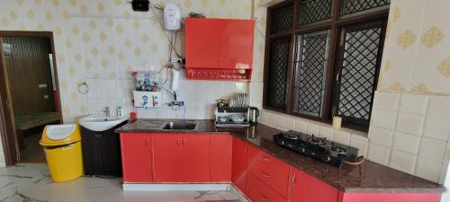 a kitchen with red cabinets and a sink at Casa Arhan 2-3-4-7-12 BHK Luxury Penthouse in Mussoorie