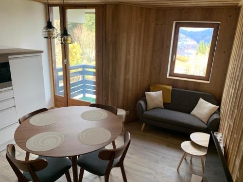 een woonkamer met een tafel en stoelen en een bank bij Cocon familial au pied des pistes in Morillon