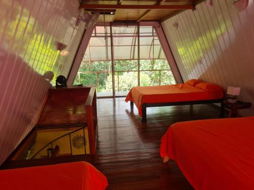 PiedrasにあるCasa El Jardínのベッド2台と大きな窓が備わる客室です。