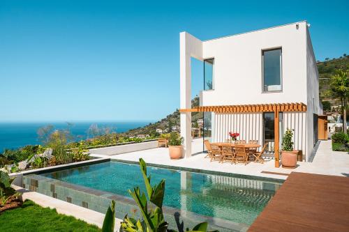 a villa with a swimming pool and a dining table at Serenity Villa on the Cliff with climatized pool in Sauzal