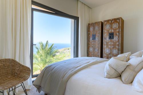 a bedroom with a bed and a large window at Serenity Villa on the Cliff with climatized pool in Sauzal