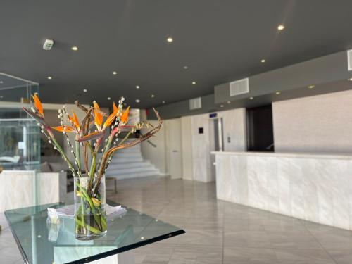 a vase of flowers on a glass table in a lobby at Hotel Nafpaktos in Nafpaktos