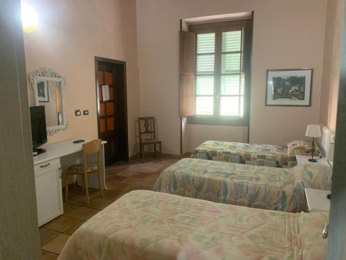 Habitación de hotel con 2 camas, escritorio y TV. en B&B Julia's Friends en Sassari