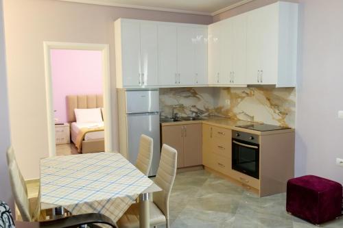 a kitchen with white cabinets and a table and a dining room at Brothers LR in Sarandë