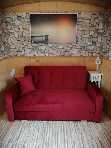 ein rotes Sofa in einem Zimmer mit einer Steinmauer in der Unterkunft Schäferwagen Rotkelchen in Ratingen