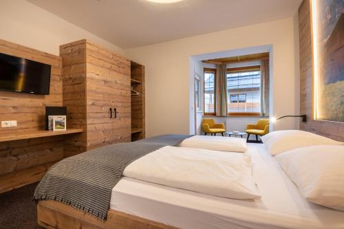 a bedroom with two beds and a flat screen tv at Aparthotel Tyrol in Lermoos