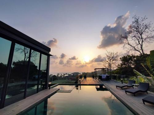a house with a pool with the sunset in the background at Villa Obsidian, sea view and walk to Choeng Mon beach in Choeng Mon Beach