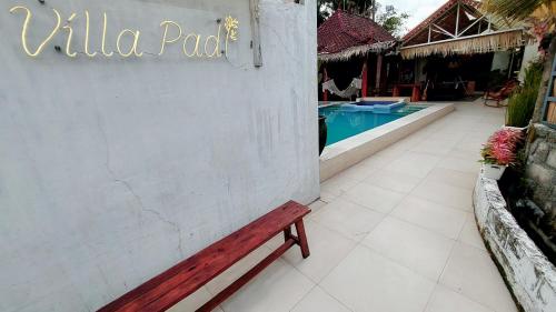 a wooden bench sitting next to a wall next to a swimming pool at Villa Padi Pakem in Pakem