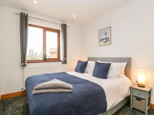 Un dormitorio con una cama con una manta azul y una ventana. en Delphine Lodge, Meadow View Lodges, en Burnham-on-Sea