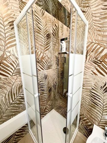 a shower in a bathroom with palm leaves wallpaper at Le Grotte delle Meraviglie in Lustignano