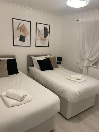 two beds in a white room with pictures on the wall at Stylish 1 Bedroom close to Tooting Bec Station in London