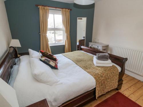 una camera da letto con letto, cuscini e finestra di Bridge End Cottage a Morpeth