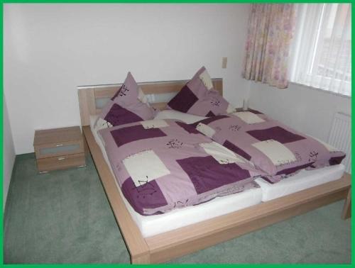 a bedroom with a bed with purple sheets and pillows at Haus-Fechtig-Wohnung-TypB-Parterre in Bonndorf im Schwarzwald