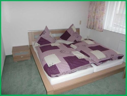ボンドルフ・イム・シュヴァルツヴァルトにあるHaus-Fechtig-Wohnung-TypB-Parterreのベッドルーム1室(紫のシーツと枕が備わるベッド1台付)