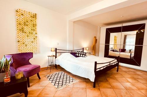 a bedroom with a bed and a chair and a mirror at Künstler Ferienwohnung am Weilburger Schloss, Marktplatz 9 in Weilburg