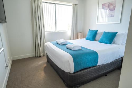 a bedroom with a large bed with blue pillows at Pavillions on 1770 in Agnes Water