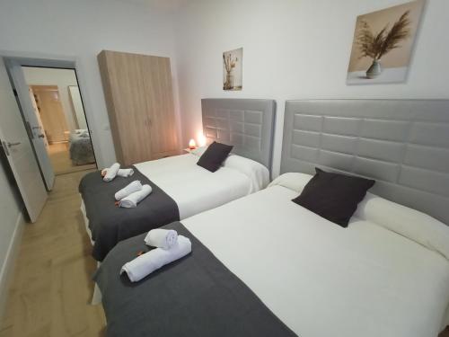 two beds in a hotel room with white sheets at Casa FERTONIA in Fuentes de Andalucía
