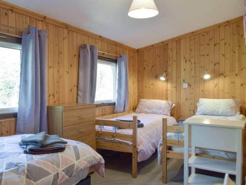 two beds in a room with wood paneled walls at Merlins Cabin in Cenarth