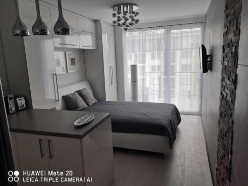 a bedroom with a bed and a desk and a window at Sunset Home Apartman in Siófok