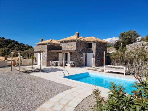 a villa with a swimming pool in front of a house at Palazzo Greco Villas in Agia Galini