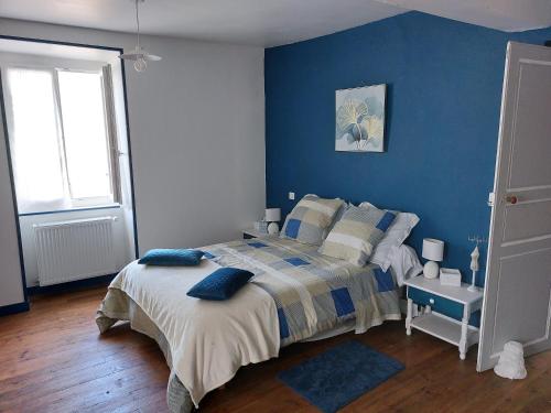 1 dormitorio con paredes azules y 1 cama con almohadas en Les chambres au pied du Rey, en Sainte-Colome
