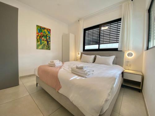 a bedroom with a bed with white sheets and a window at 8 Hulda - By Beach Apartments TLV in Tel Aviv