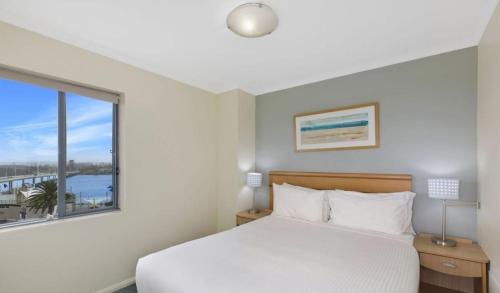 Un dormitorio con una cama y una ventana grande. en The Entrance Waterfront Apartment 525, en The Entrance