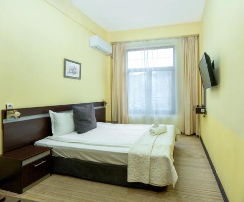 a hotel room with a bed and a window at Family Hotel Central in Shumen