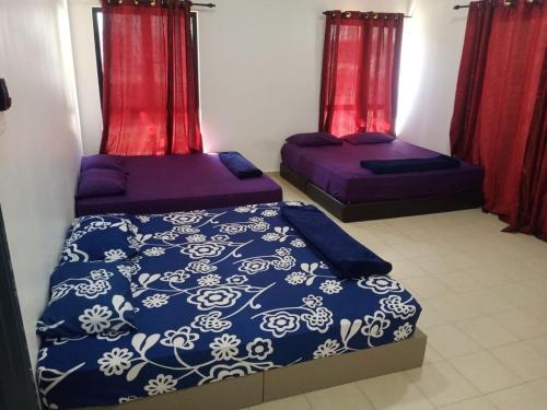 two beds in a room with red curtains at Pangkor L29, Dream Island Homestay in Kampong Sungai Udang