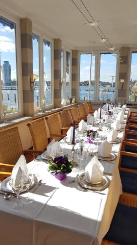 a long dining room with white tables and chairs at Akzent Hotel Strandhalle in Schleswig