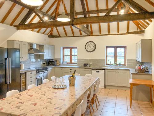 a kitchen with a long table with chairs and a clock at The Hop Bind in Bromyard