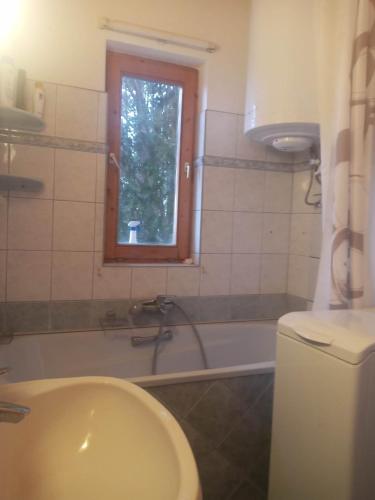 a bathroom with a tub and a toilet and a window at Felsőörsi Nyugalom in Felsőörs