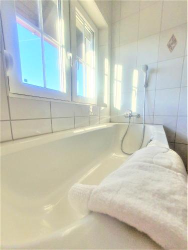 a white bathroom with a bath tub with a towel at Pension Schwartzwirt in Neusiedl am Steinfelde