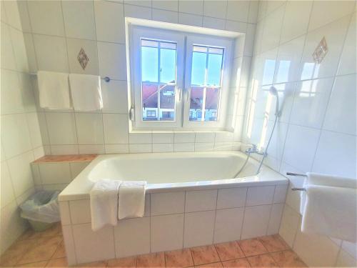 a white bathroom with a tub and a window at Pension Schwartzwirt in Neusiedl am Steinfelde