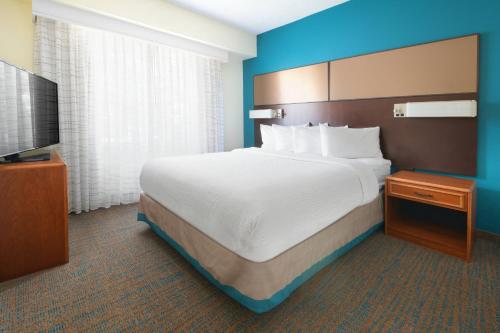 a hotel room with a large bed and a flat screen tv at Residence Inn Dallas Park Central in Dallas