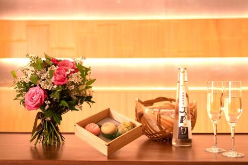 a table with a vase of flowers and a bottle of wine at THE JUNEI HOTEL Kyoto in Kyoto
