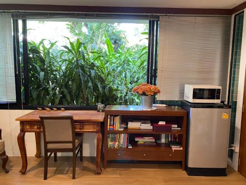 a kitchen with a table with a microwave and a window at Cozycomo Bangkok in Bangkok
